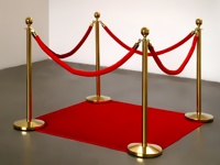 Aukso spalvos barjerų stoveliai sujungti ratu ant raudono kilimo