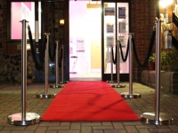 Barriers with a red carpet at the entrance of the store at night.