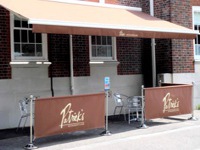 Outdoor cafe tables are enclosed by floor stands with advertising.