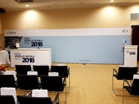 Konferencijos siena su temos pavadinimu, stalas, kėdės ir tribūna salėje