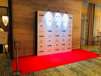 A stand with a poster and a red carpet, rope barriers on the sides