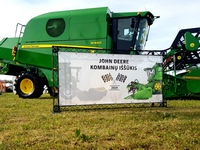 A combine harvester and a poster with an advertising inscription on the stand next to it