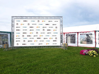 Outdoor promotional prize-giving stand with sponsors' logos on the grass